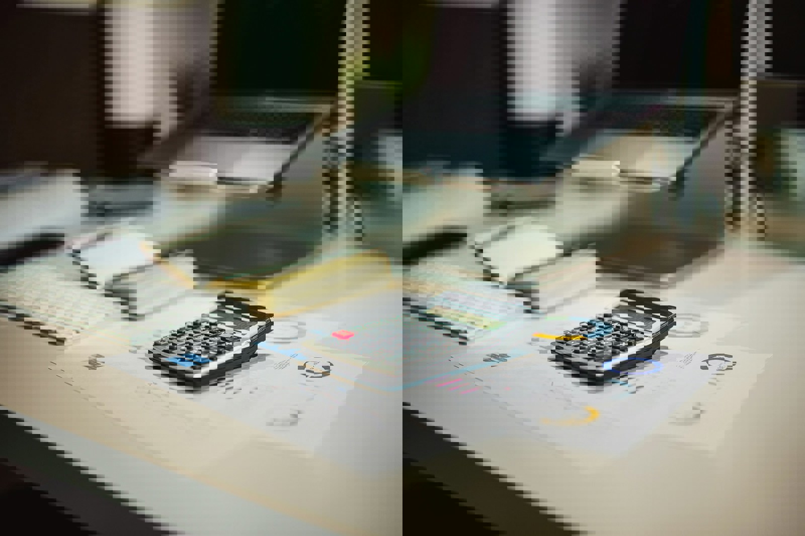 A calculator next to a keyboard and notebook